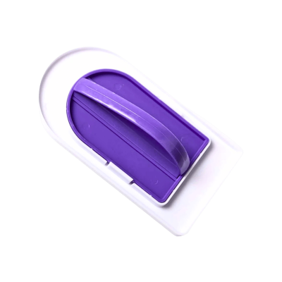 White handheld plastic device with a purple inner insert or slider visible in a recessed oval cavity.