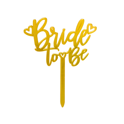 Gold cake topper reading 'Bride to Be' with heart accents on a white background, decorative cake decoration
